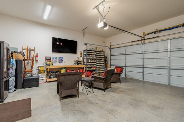 garage with a garage door opener and stainless steel fridge