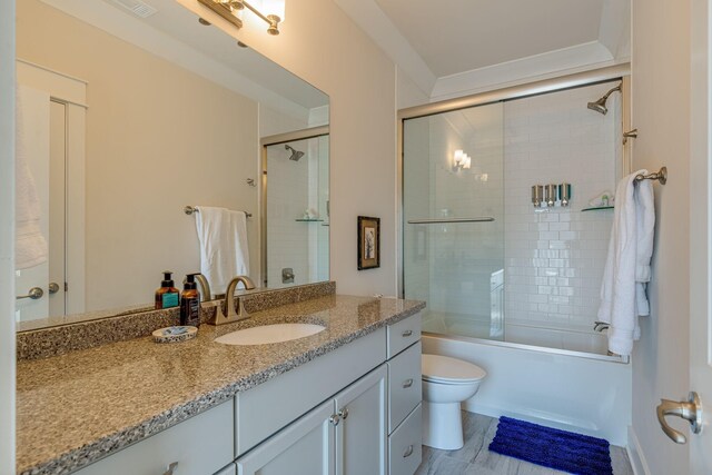 full bathroom with enclosed tub / shower combo, vanity, and toilet