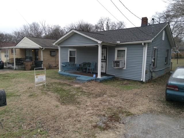 view of front facade with cooling unit, a porch, and a front lawn