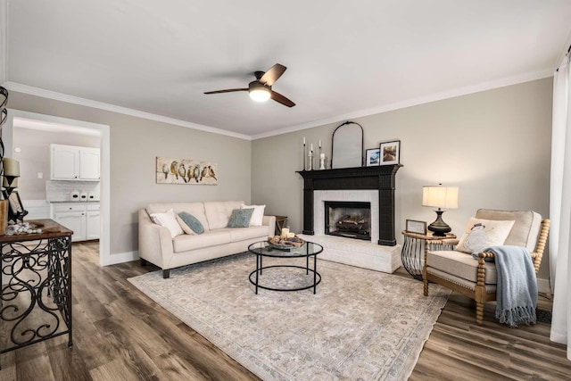 living room featuring ornamental molding, ceiling fan, dark hardwood / wood-style flooring, and a fireplace