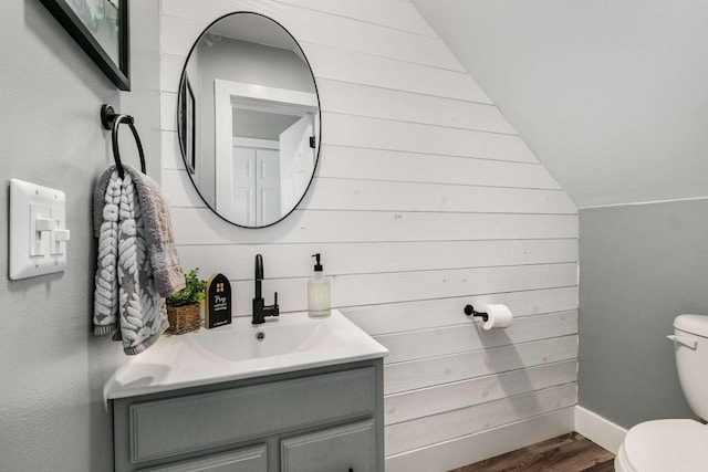 bathroom with hardwood / wood-style flooring, vanity, lofted ceiling, and toilet