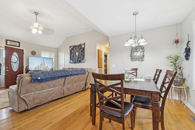 dining room with ceiling fan with notable chandelier, lofted ceiling, and light hardwood / wood-style floors