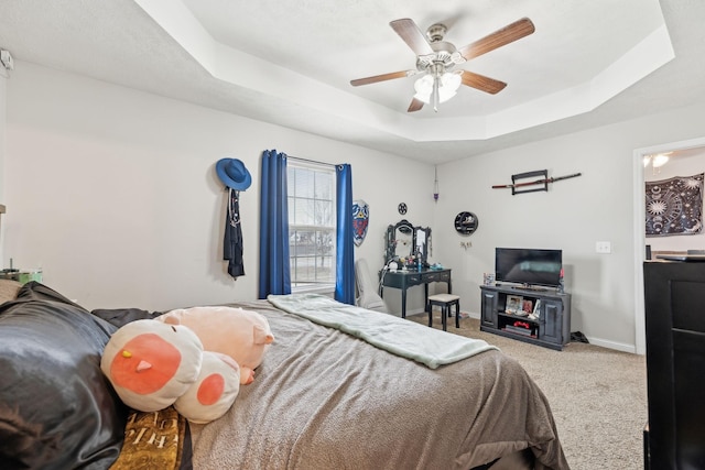 carpeted bedroom featuring a tray ceiling and ceiling fan