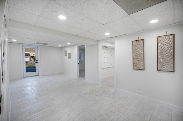 basement featuring a drop ceiling and light hardwood / wood-style floors