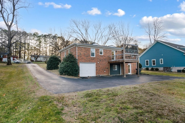 rear view of property featuring a yard, a garage, and a wooden deck