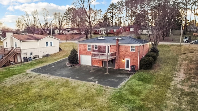 rear view of property with a garage, a wooden deck, and a yard