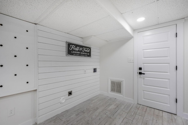 clothes washing area with wooden walls, light hardwood / wood-style floors, and hookup for an electric dryer