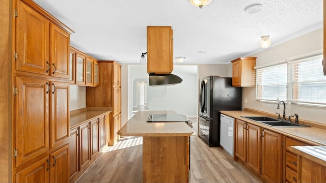 kitchen featuring sink, light hardwood / wood-style flooring, dishwasher, a center island, and black fridge