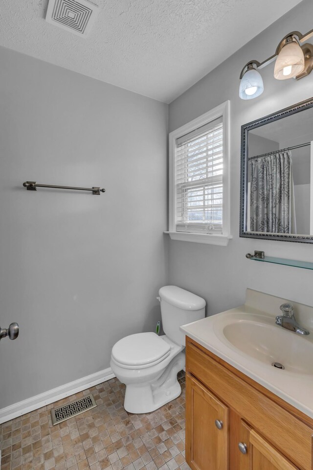 bathroom with a shower with curtain, vanity, toilet, and a textured ceiling