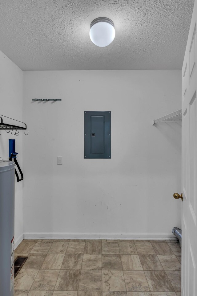 clothes washing area featuring electric panel, water heater, and a textured ceiling