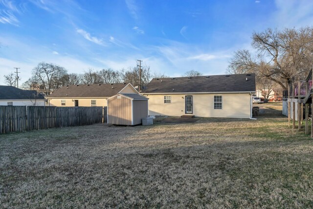 back of property featuring a storage unit and a yard