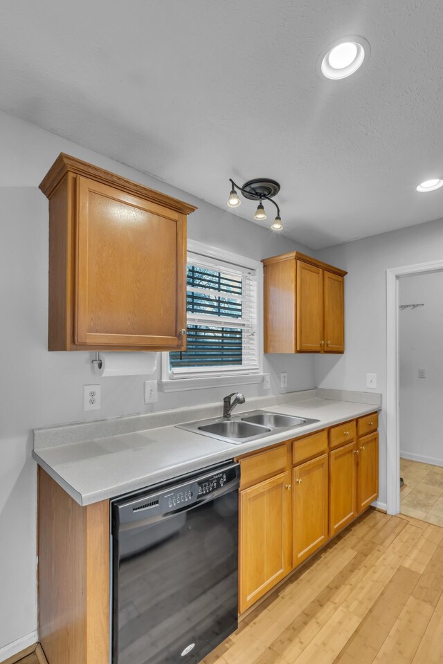 kitchen with dishwasher, sink, a textured ceiling, and light wood-type flooring