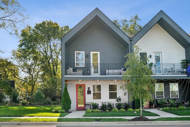 view of front of property featuring a balcony and a front yard