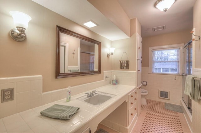 bathroom featuring tile patterned floors, toilet, sink, and tile walls