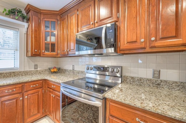 kitchen featuring light stone counters, appliances with stainless steel finishes, decorative backsplash, and light tile patterned floors