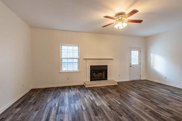 unfurnished living room featuring a healthy amount of sunlight, a fireplace with raised hearth, and dark wood-type flooring