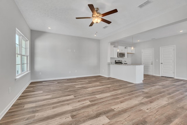 unfurnished living room featuring recessed lighting, visible vents, light wood-style flooring, and baseboards