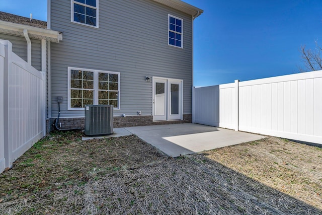 rear view of house featuring a patio area, a fenced backyard, stone siding, and cooling unit