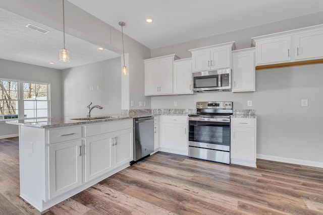 kitchen with stainless steel appliances, a sink, white cabinets, light stone countertops, and pendant lighting