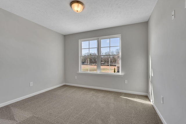 carpeted spare room with baseboards and a textured ceiling