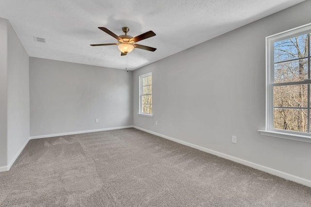 carpeted empty room featuring baseboards, a textured ceiling, visible vents, and a ceiling fan