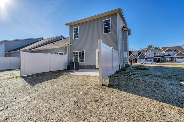 rear view of house featuring a patio, a residential view, an attached garage, fence, and central air condition unit