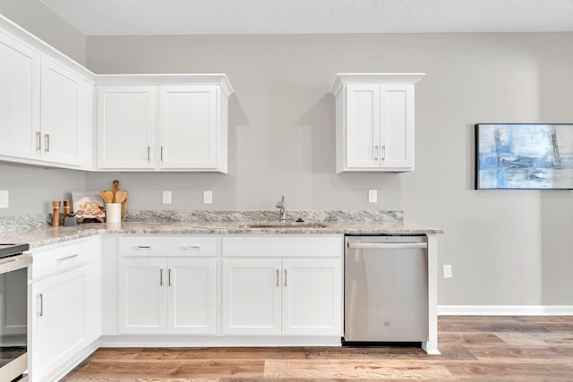 kitchen with light stone counters, a sink, white cabinetry, light wood-style floors, and stainless steel dishwasher