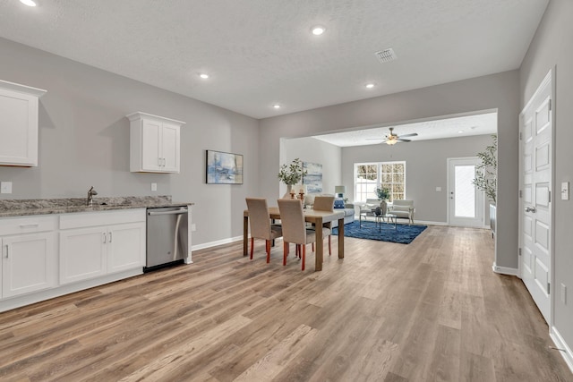 kitchen with visible vents, dishwasher, open floor plan, light stone countertops, and white cabinetry