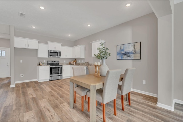 dining room featuring light wood-style flooring, recessed lighting, visible vents, and baseboards