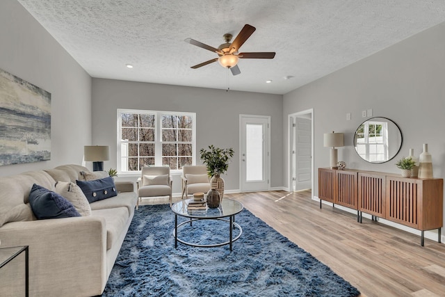 living room with recessed lighting, light wood-style flooring, ceiling fan, a textured ceiling, and baseboards