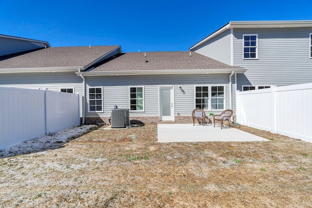 back of house featuring central AC unit, roof with shingles, a patio area, and a fenced backyard