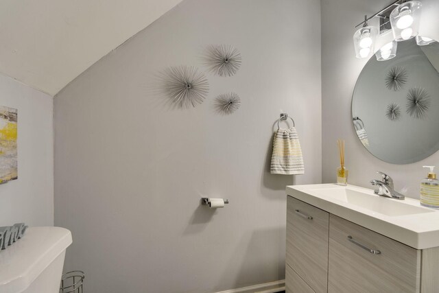 bathroom featuring vanity, vaulted ceiling, and toilet