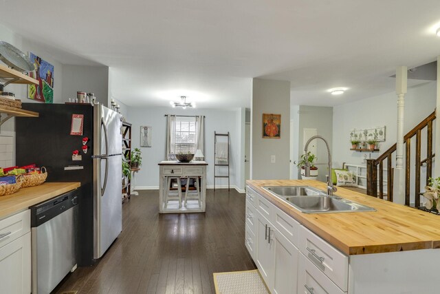 kitchen with sink, wooden counters, appliances with stainless steel finishes, white cabinetry, and dark hardwood / wood-style flooring