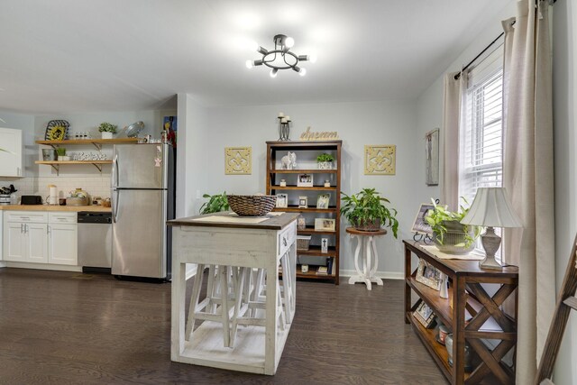 kitchen featuring appliances with stainless steel finishes, dark hardwood / wood-style floors, white cabinets, and decorative backsplash