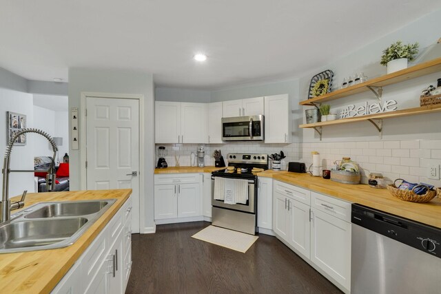 kitchen with sink, dark wood-type flooring, stainless steel appliances, white cabinets, and wood counters