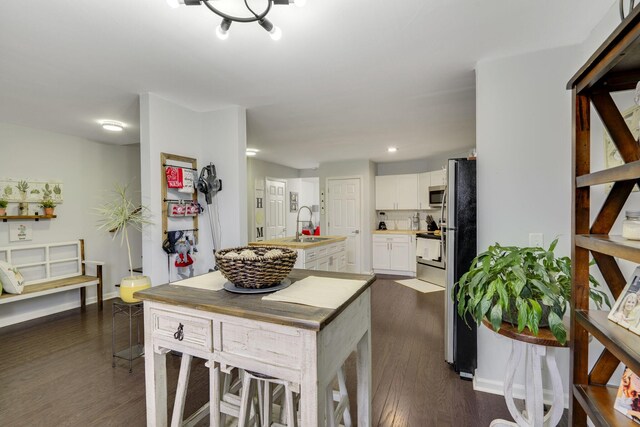 kitchen with sink, white cabinetry, appliances with stainless steel finishes, dark hardwood / wood-style floors, and an island with sink