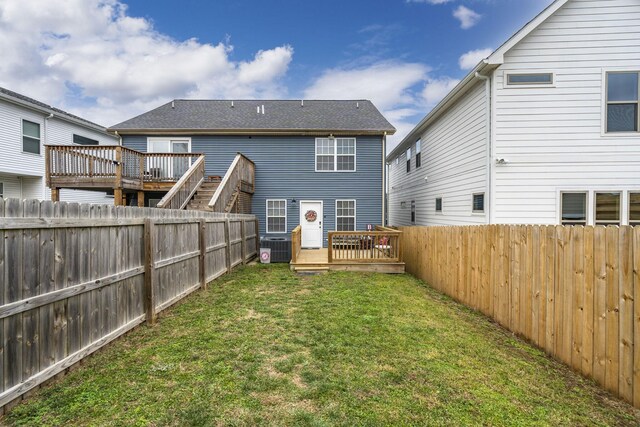 rear view of house with central AC unit, a deck, and a lawn