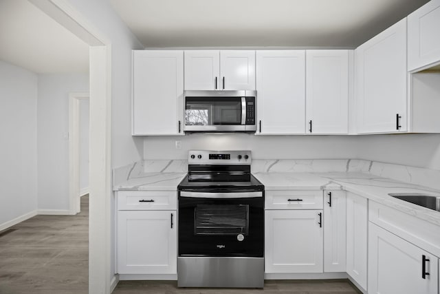 kitchen with appliances with stainless steel finishes, light stone countertops, and white cabinets