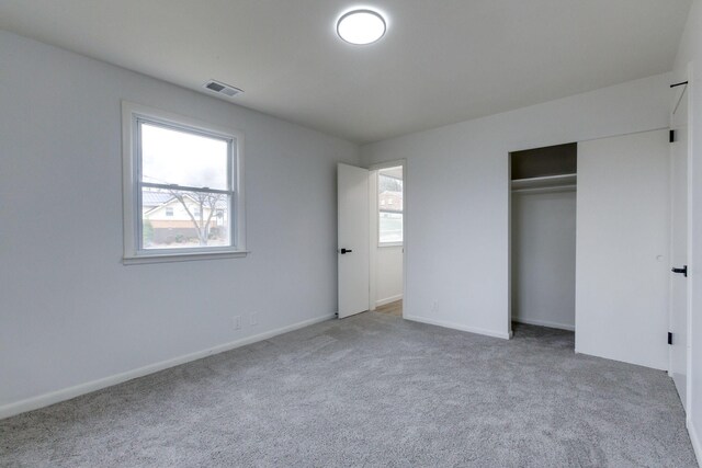 unfurnished bedroom featuring multiple windows, light colored carpet, and a closet