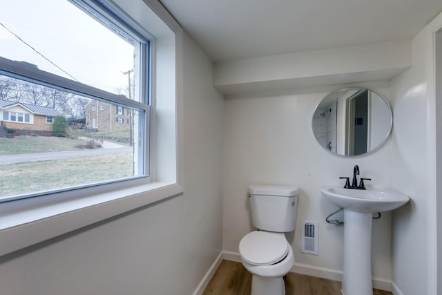 bathroom featuring wood-type flooring, toilet, sink, and a wealth of natural light