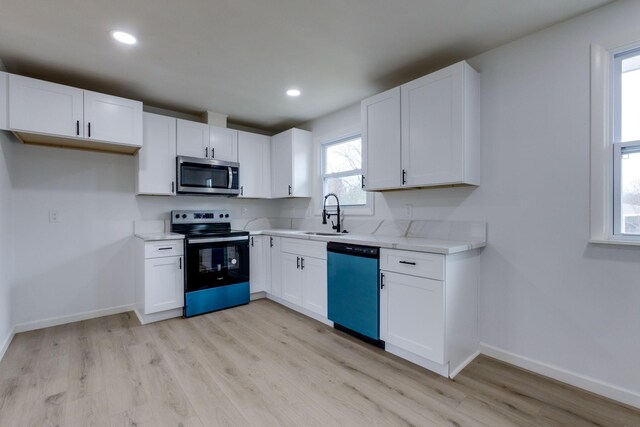 kitchen featuring light wood-type flooring, appliances with stainless steel finishes, sink, and white cabinets