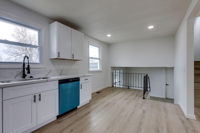 kitchen with sink, white cabinetry, light stone counters, stainless steel dishwasher, and light hardwood / wood-style floors