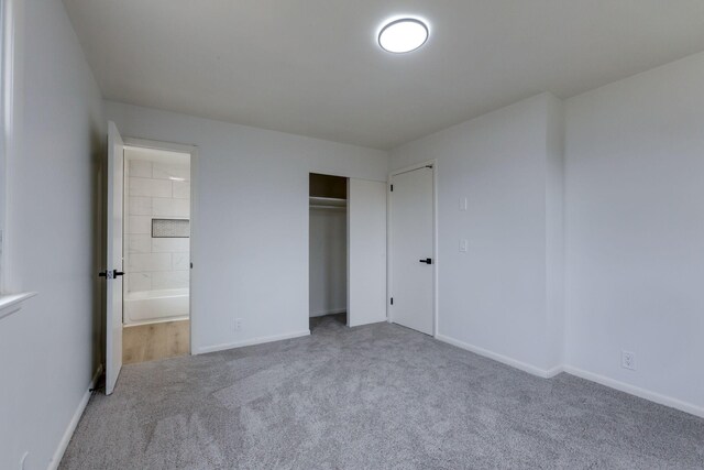 unfurnished bedroom with ensuite bathroom, carpet floors, and a closet