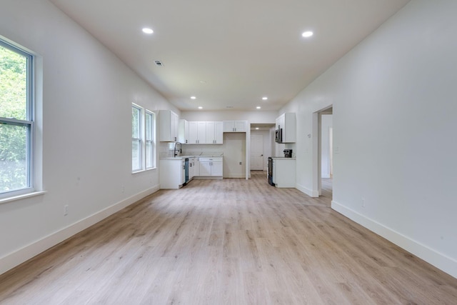 unfurnished living room with sink and light hardwood / wood-style floors