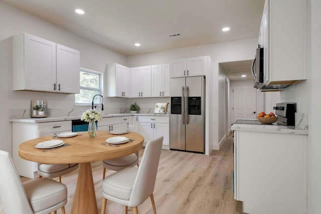 kitchen with white cabinetry, appliances with stainless steel finishes, sink, and light wood-type flooring