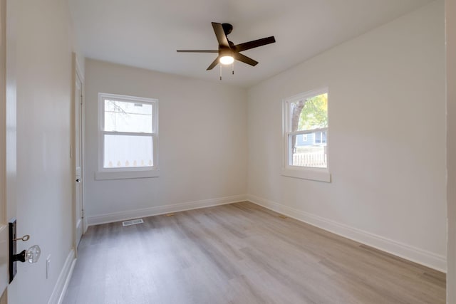 empty room featuring ceiling fan, a wealth of natural light, and light wood-type flooring