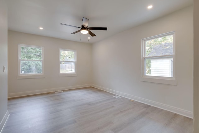 spare room featuring ceiling fan, light hardwood / wood-style flooring, and a healthy amount of sunlight