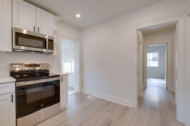 kitchen featuring stainless steel appliances, white cabinets, and light hardwood / wood-style floors