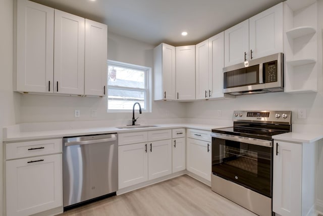 kitchen with stainless steel appliances, light hardwood / wood-style floors, sink, and white cabinets