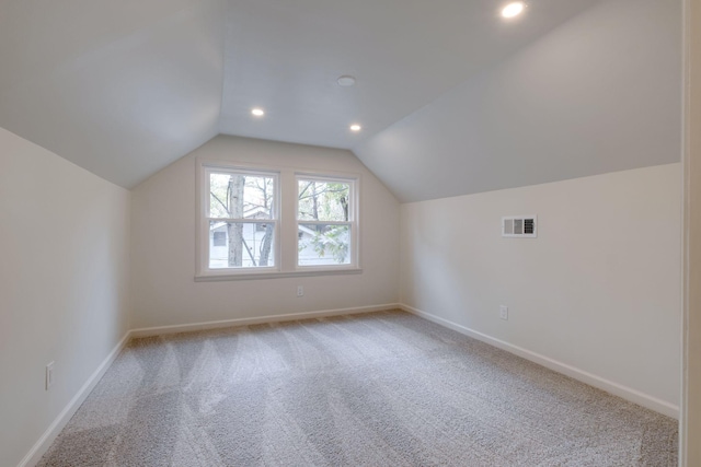 additional living space featuring lofted ceiling and light colored carpet